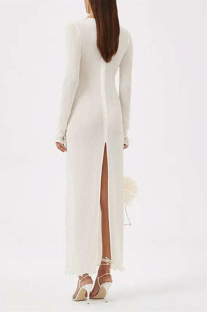 White - A woman wearing a long-sleeved, white ribbed knit maxi dress featuring a deep plunging neckline decorated with large 3D floral appliqués.
