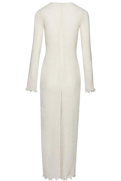 White - A woman wearing a long-sleeved, white ribbed knit maxi dress featuring a deep plunging neckline decorated with large 3D floral appliqués.