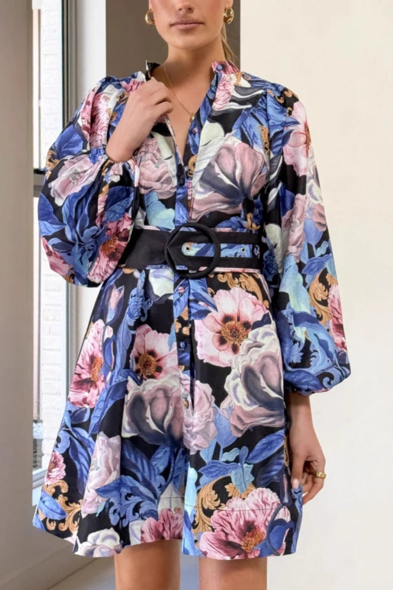 A woman modeling a woven floral long-sleeve mini shirtdress featuring a button-down front, voluminous balloon sleeves, and a wide waist belt with a large circular buckle.