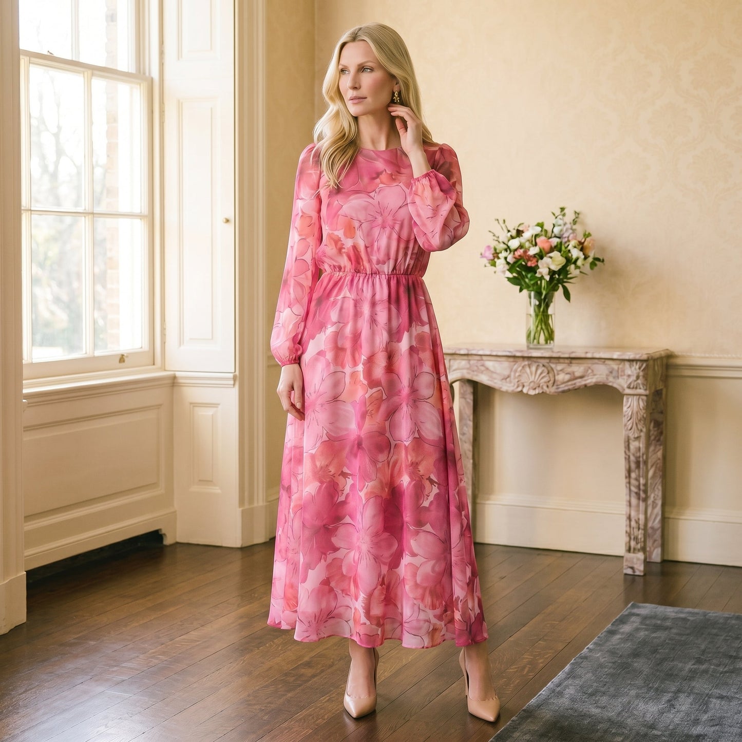 Pink - A woman stands wearing a blue and purple floral print chiffon midi dress with long sheer puff sleeves, a high neckline, and an A-line skirt, holding a gold clutch.