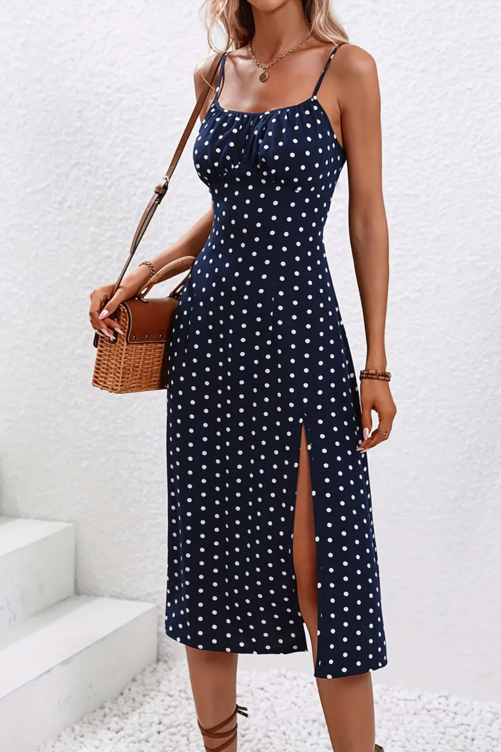 Green Dot - A woman wearing a black midi-length slip dress with a delicate red and white floral print, featuring thin spaghetti straps, a ruched bust, and a high front slit.