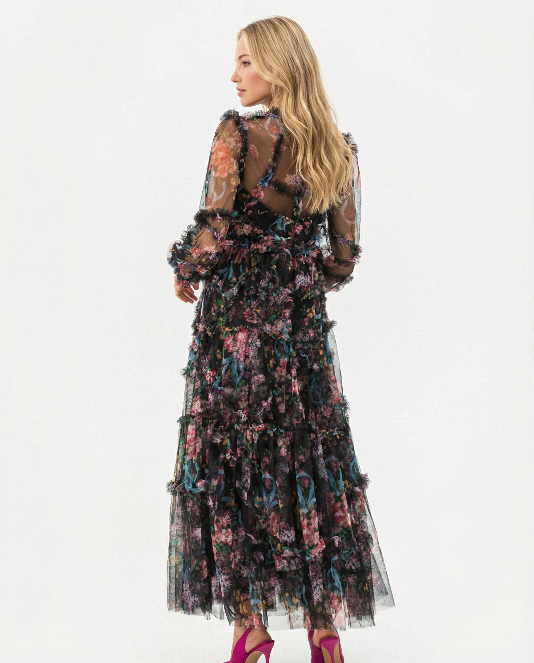 Black - A model wearing a high-neck, long-sleeved maxi dress in black tulle with a vibrant multi-coloured floral print, featuring tiered ruffles and sheer sleeves.