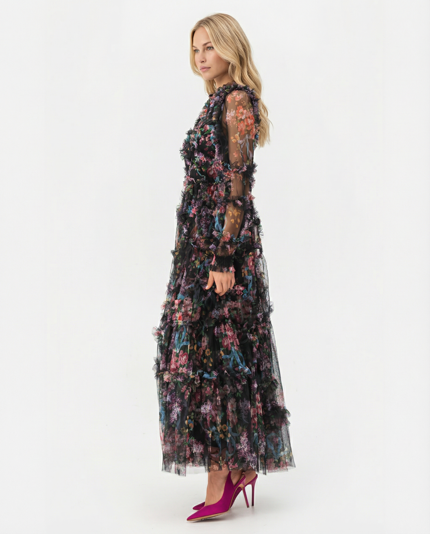 Black - A model wearing a high-neck, long-sleeved maxi dress in black tulle with a vibrant multi-coloured floral print, featuring tiered ruffles and sheer sleeves.
