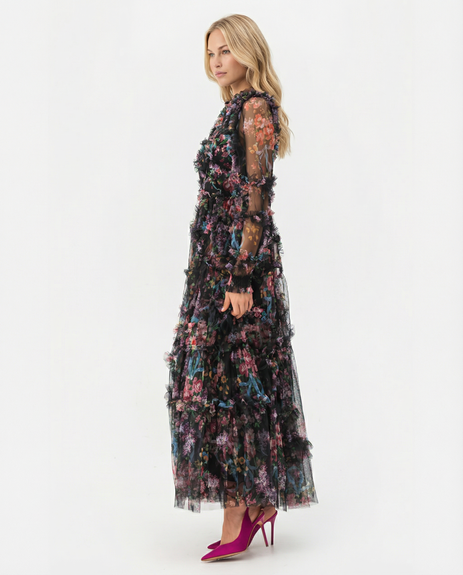 Black - A model wearing a high-neck, long-sleeved maxi dress in black tulle with a vibrant multi-coloured floral print, featuring tiered ruffles and sheer sleeves.