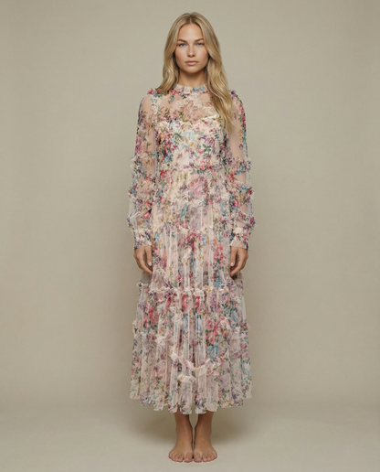 Apricot - A model wearing a high-neck, long-sleeved maxi dress in black tulle with a vibrant multi-coloured floral print, featuring tiered ruffles and sheer sleeves.
