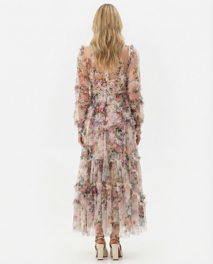 Apricot - A model wearing a high-neck, long-sleeved maxi dress in black tulle with a vibrant multi-coloured floral print, featuring tiered ruffles and sheer sleeves.