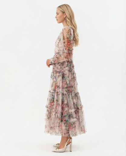 Apricot - A model wearing a high-neck, long-sleeved maxi dress in black tulle with a vibrant multi-coloured floral print, featuring tiered ruffles and sheer sleeves.