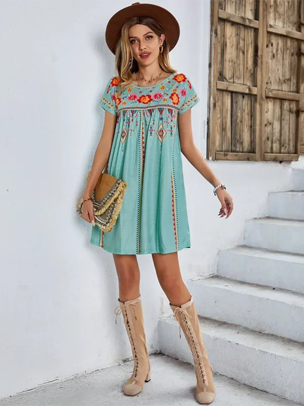 Green - Black short-sleeve mini dress featuring vibrant geometric and floral folkloric patterns with a gathered yoke and relaxed shift silhouette.