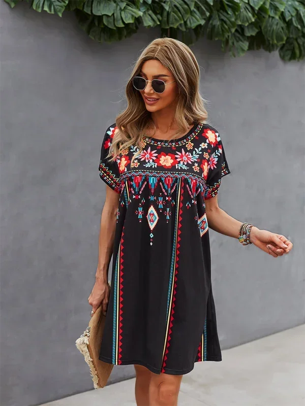 Black - Black short-sleeve mini dress featuring vibrant geometric and floral folkloric patterns with a gathered yoke and relaxed shift silhouette.