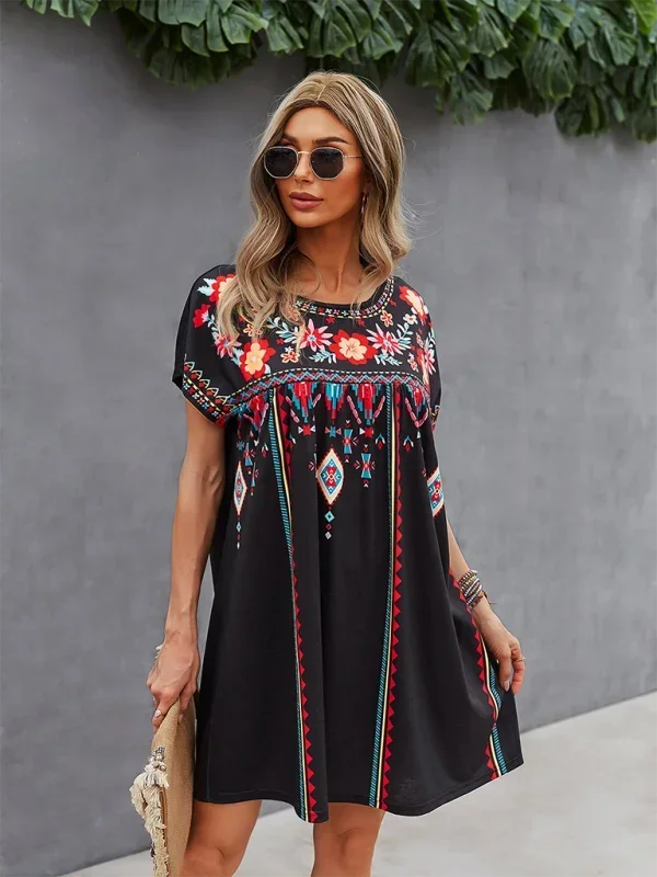 Black - Black short-sleeve mini dress featuring vibrant geometric and floral folkloric patterns with a gathered yoke and relaxed shift silhouette.