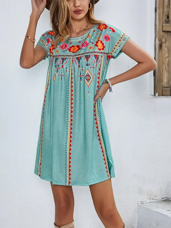Green - Black short-sleeve mini dress featuring vibrant geometric and floral folkloric patterns with a gathered yoke and relaxed shift silhouette.