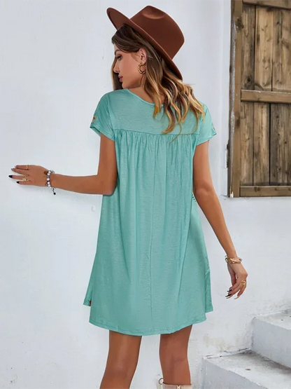 Green - Black short-sleeve mini dress featuring vibrant geometric and floral folkloric patterns with a gathered yoke and relaxed shift silhouette.