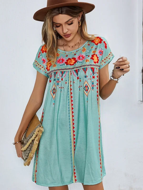 Green - Black short-sleeve mini dress featuring vibrant geometric and floral folkloric patterns with a gathered yoke and relaxed shift silhouette.