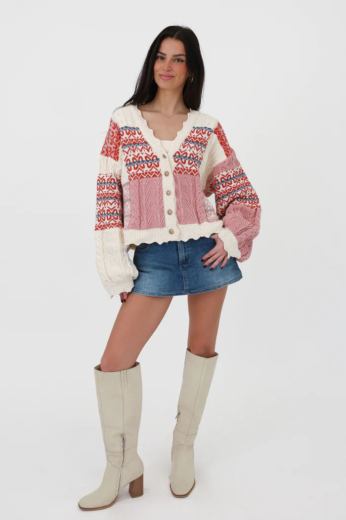 Multi-color - Women's chunky V-neck cardigan featuring a patchwork design of pink, red, and cream Fair Isle patterns and cable knit textures, finished with scalloped edges and metallic buttons.