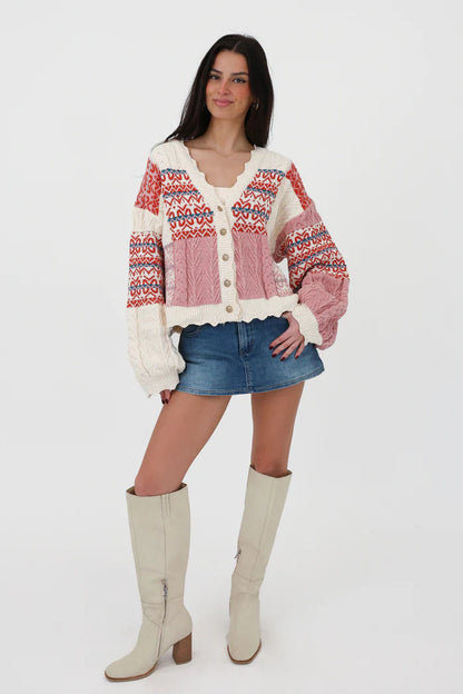 Multi-color - Women's chunky V-neck cardigan featuring a patchwork design of pink, red, and cream Fair Isle patterns and cable knit textures, finished with scalloped edges and metallic buttons.