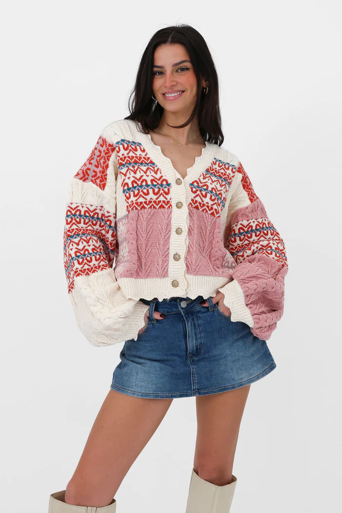 Multi-color - Women's chunky V-neck cardigan featuring a patchwork design of pink, red, and cream Fair Isle patterns and cable knit textures, finished with scalloped edges and metallic buttons.
