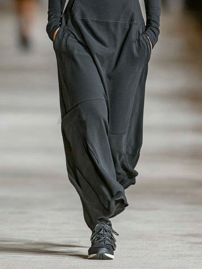 Black - A model walks a runway wearing a black, long-sleeved, high-neck maxi dress with a half-zip front, fitted bodice, dropped waist, and relaxed skirt with side pockets.