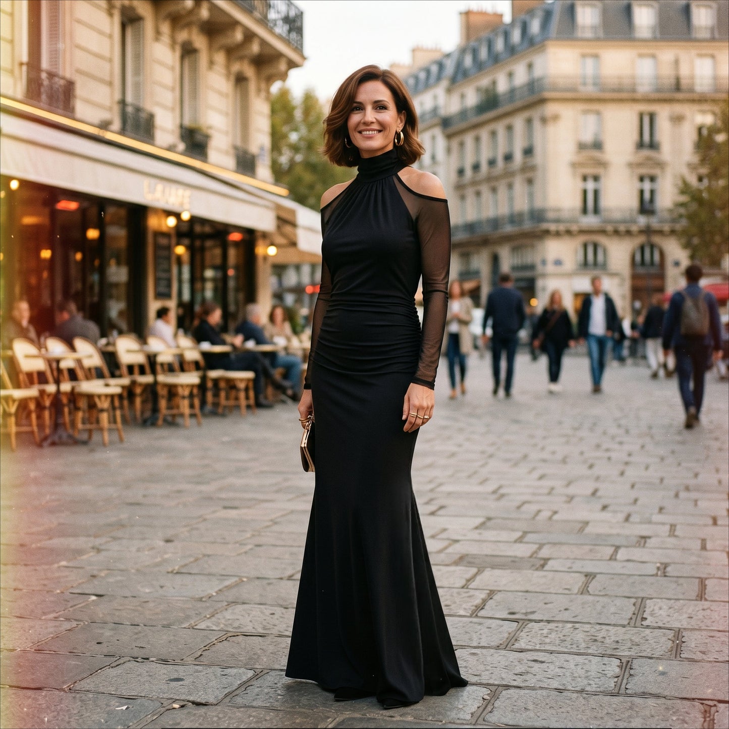 2XL(18) - A woman wearing a floor-length black evening gown featuring a high mock neckline, sheer long mesh sleeves with cold-shoulder cutouts, and a ruched fitted bodice that drapes into a subtle mermaid silhouette.