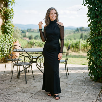2XL(18) - A woman wearing a floor-length black evening gown featuring a high mock neckline, sheer long mesh sleeves with cold-shoulder cutouts, and a ruched fitted bodice that drapes into a subtle mermaid silhouette.