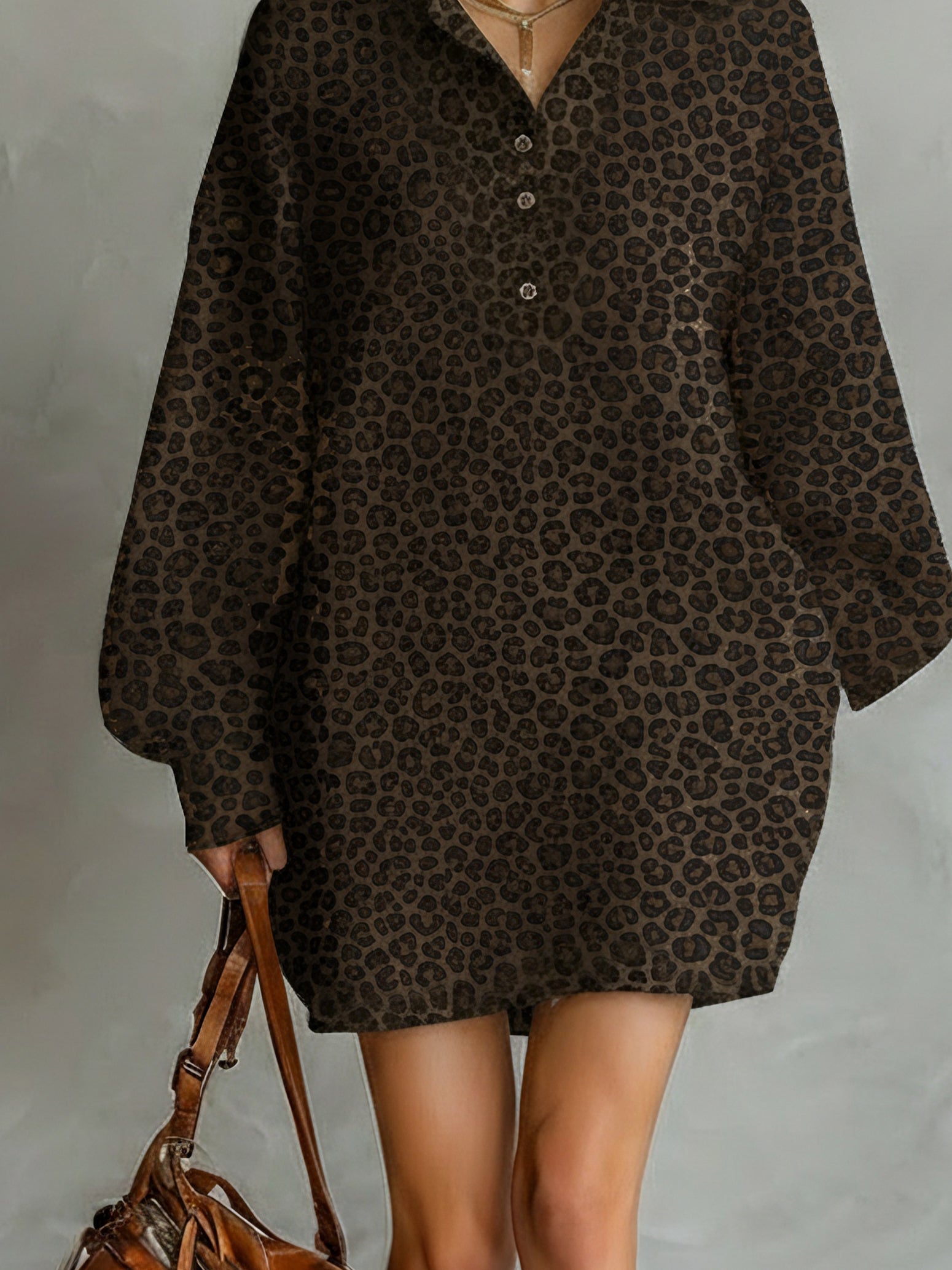 Brown - A model wears a relaxed-fit, long-sleeve mini shirt dress featuring a dark brown leopard print pattern, styled with a point collar and partial button placket.