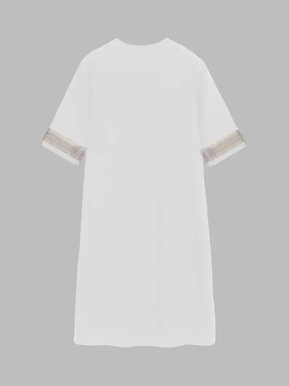 White - A woman wearing a white, knee-length shift dress made of textured linen-like fabric, featuring intricate beige crochet lace trim along the deep V-neckline and elbow-length sleeve cuffs.