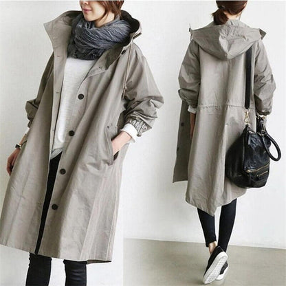 Grey 2 - A model wearing a light grey mid-length hooded coat with a single-breasted button front, styled with a black scarf and black pants against a plain white background.