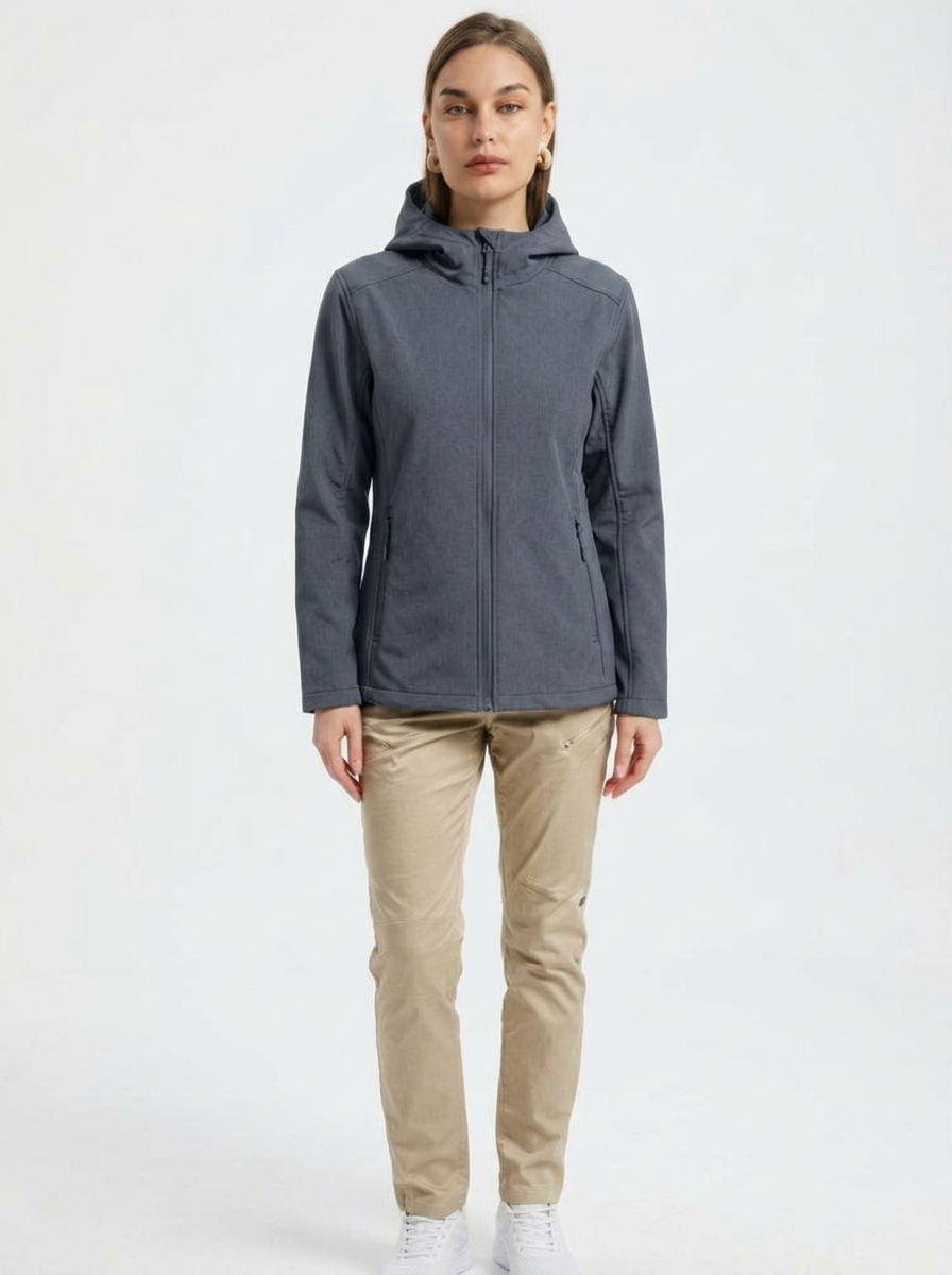 Gray - A woman wearing a structured olive green matte technical hooded jacket with a front zip closure, panelled seam detailing, and zippered pockets, paired with beige trousers.