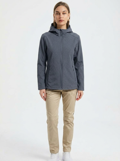 Gray - A woman wearing a structured olive green matte technical hooded jacket with a front zip closure, panelled seam detailing, and zippered pockets, paired with beige trousers.