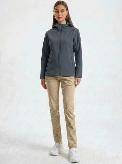 Gray - A woman wearing a structured olive green matte technical hooded jacket with a front zip closure, panelled seam detailing, and zippered pockets, paired with beige trousers.