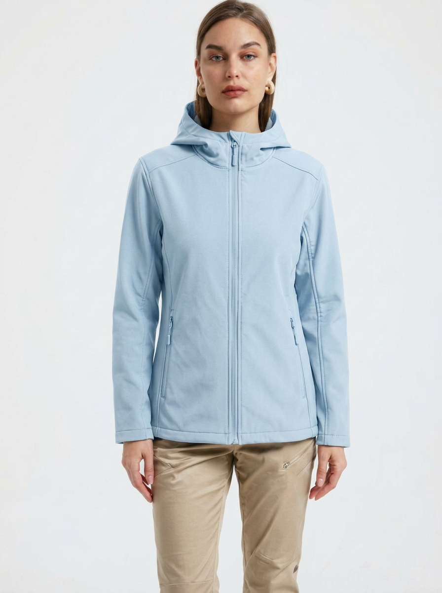 Blue - A woman wearing a structured olive green matte technical hooded jacket with a front zip closure, panelled seam detailing, and zippered pockets, paired with beige trousers.