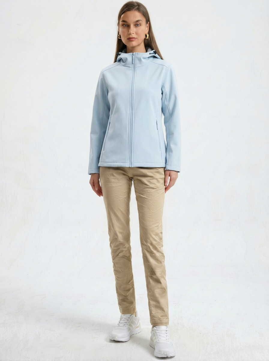 Blue - A woman wearing a structured olive green matte technical hooded jacket with a front zip closure, panelled seam detailing, and zippered pockets, paired with beige trousers.