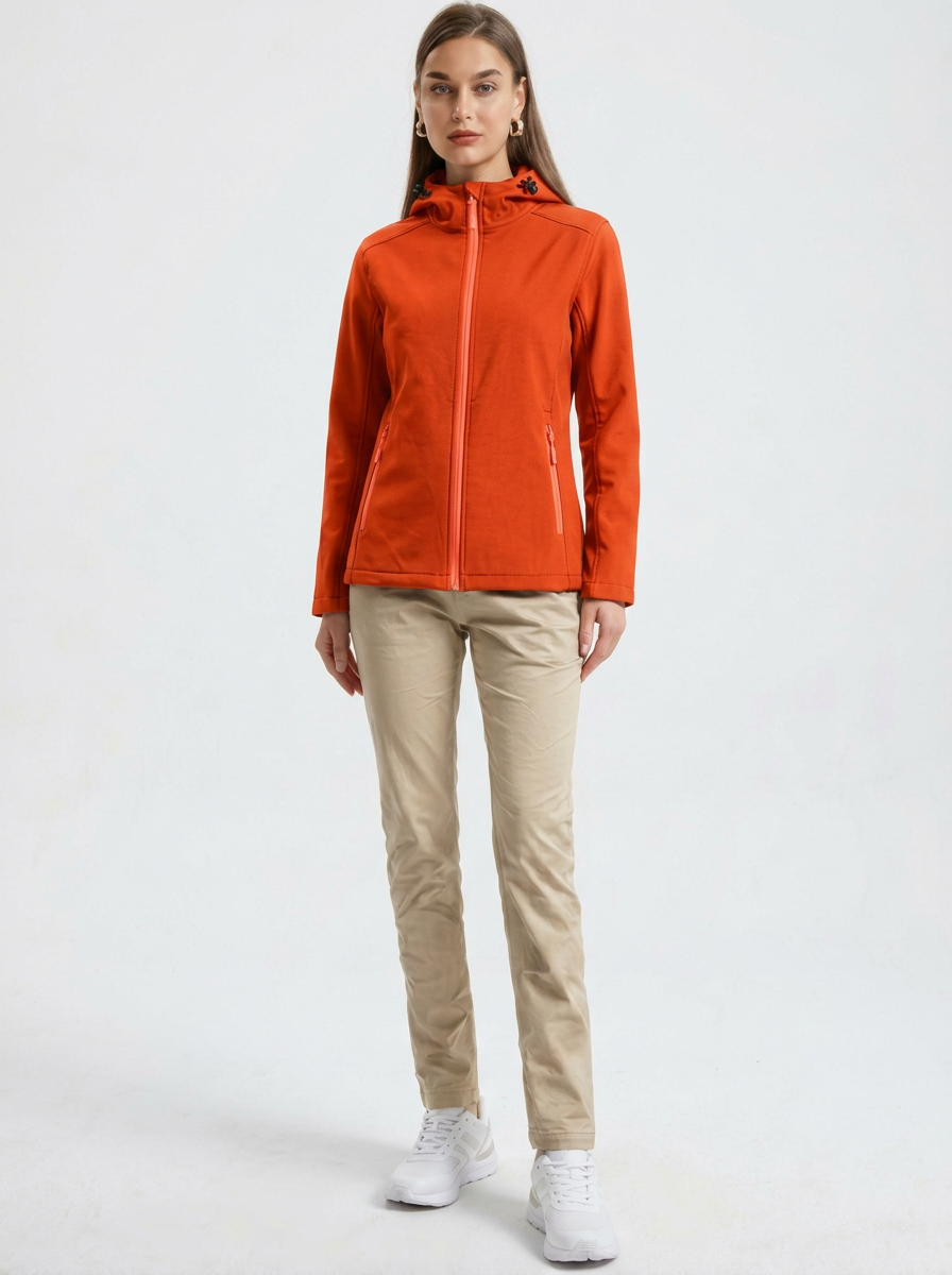 Orange - A woman wearing a structured olive green matte technical hooded jacket with a front zip closure, panelled seam detailing, and zippered pockets, paired with beige trousers.
