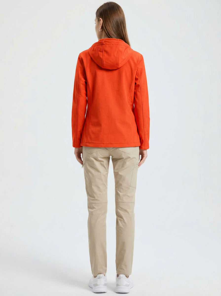 Orange - A woman wearing a structured olive green matte technical hooded jacket with a front zip closure, panelled seam detailing, and zippered pockets, paired with beige trousers.