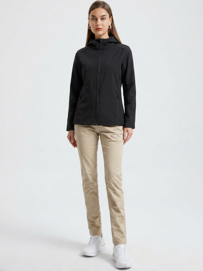 Black - A woman wearing a structured olive green matte technical hooded jacket with a front zip closure, panelled seam detailing, and zippered pockets, paired with beige trousers.