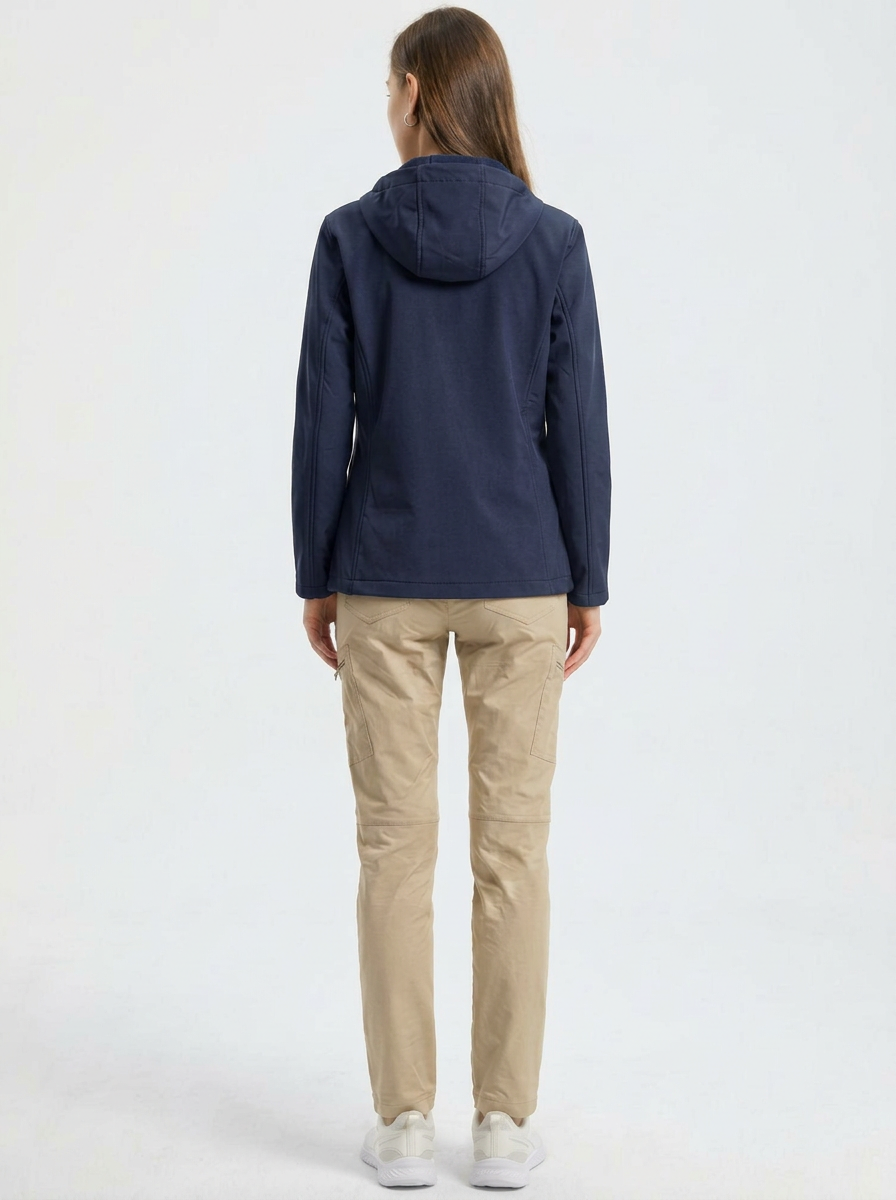 Navy - A woman wearing a structured olive green matte technical hooded jacket with a front zip closure, panelled seam detailing, and zippered pockets, paired with beige trousers.