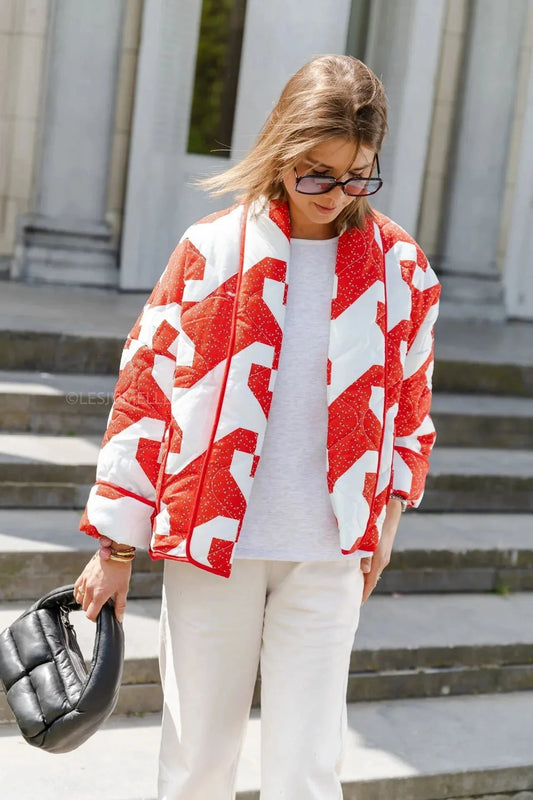 Women's relaxed-fit open-front quilted jacket featuring a bold red and white geometric block print and contrast piping, styled over a white t-shirt and trousers.