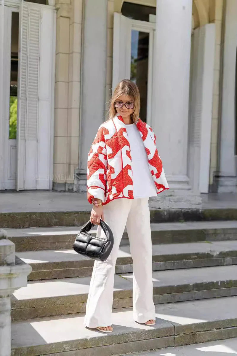 Women's relaxed-fit open-front quilted jacket featuring a bold red and white geometric block print and contrast piping, styled over a white t-shirt and trousers.