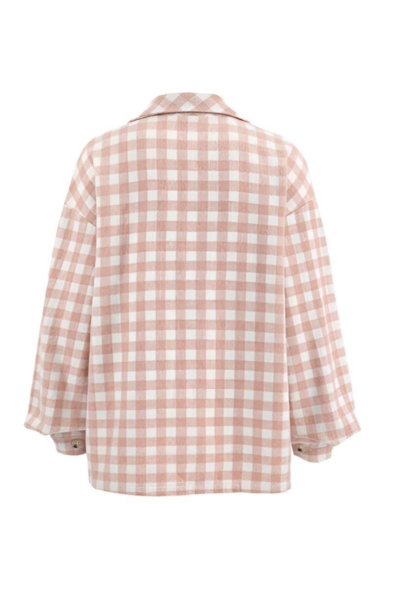 A woman taking a mirror selfie wearing an oversized, light pink and white plaid shacket over a white crop top and light wash denim jeans.