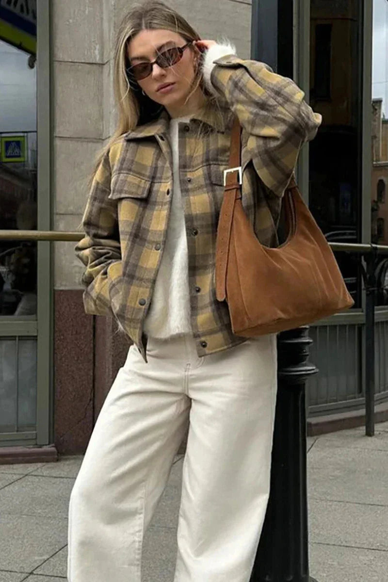 Plaid - Woman wearing an oversized yellow and brown plaid shirt jacket over a white fluffy sweater and white jeans, walking down a city street.
