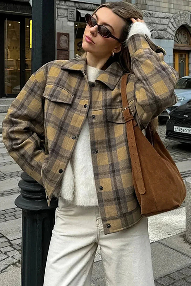 Plaid - Woman wearing an oversized yellow and brown plaid shirt jacket over a white fluffy sweater and white jeans, walking down a city street.