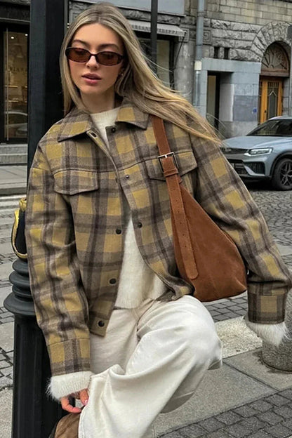Plaid - Woman wearing an oversized yellow and brown plaid shirt jacket over a white fluffy sweater and white jeans, walking down a city street.