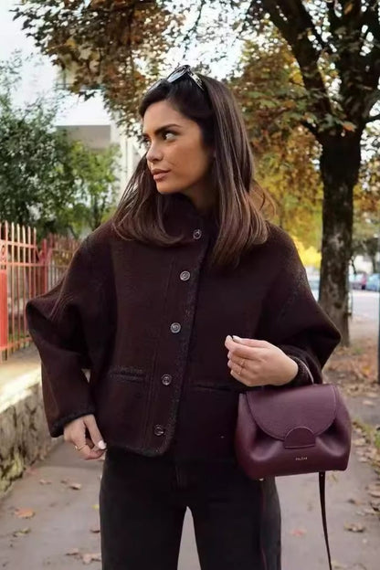 A woman wearing a dark brown, heavyweight textured cropped jacket with an oversized fit, button-front closure, and dropped shoulders, styled casually with dark denim.
