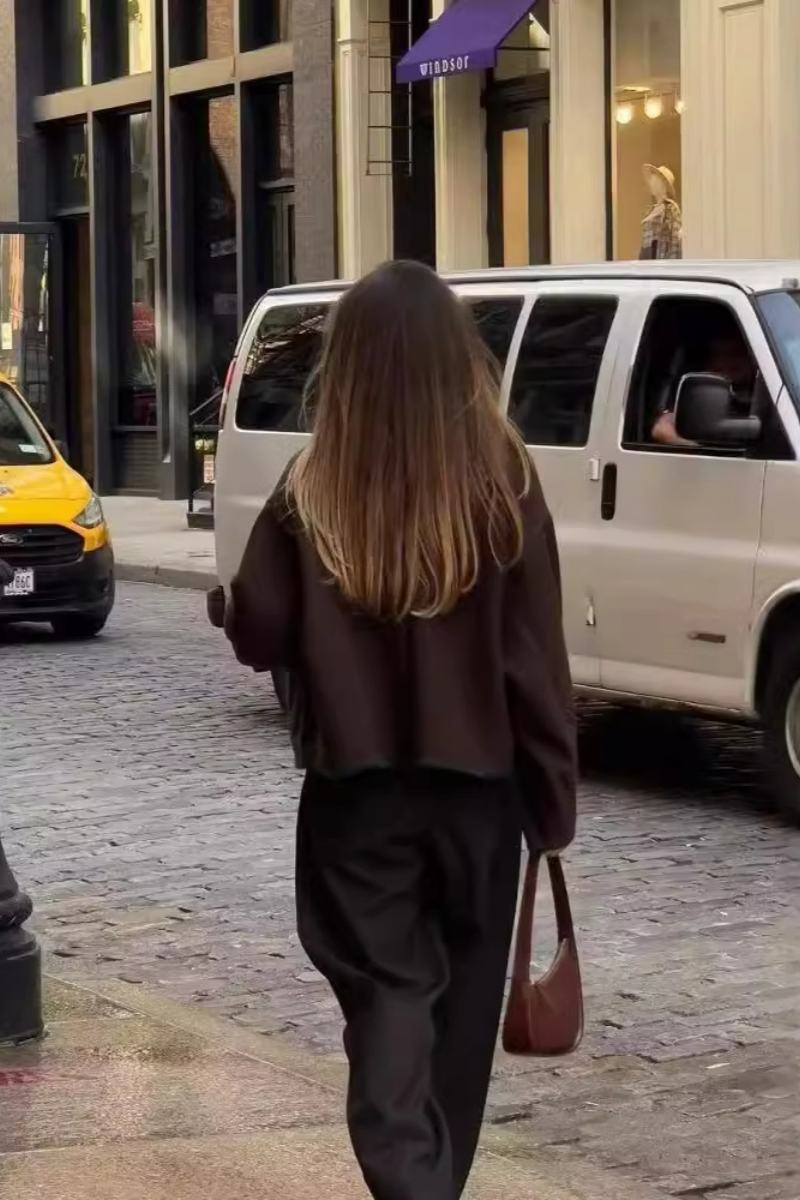 A woman wearing a dark brown, heavyweight textured cropped jacket with an oversized fit, button-front closure, and dropped shoulders, styled casually with dark denim.