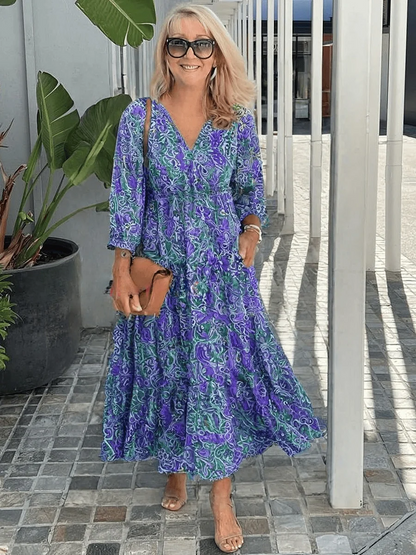 Blue - Woman wearing a flowing paisley print maxi dress with 3/4 sleeves, a tie waist, and a tiered skirt.