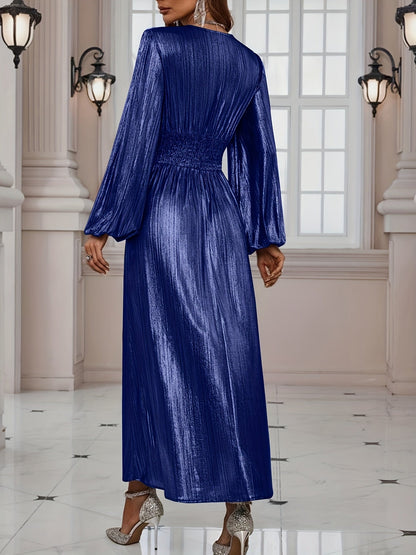 Gold - Woman wearing a shiny metallic pleated long sleeve maxi dress with a wrap bodice, banded waist, and high leg slit, standing in a formal indoor setting.
