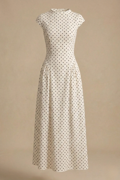 White - Model wearing a white and black polka dot maxi dress featuring a high neckline, cap sleeves, a fitted bodice with a basque waist, and a full pleated A-line skirt.