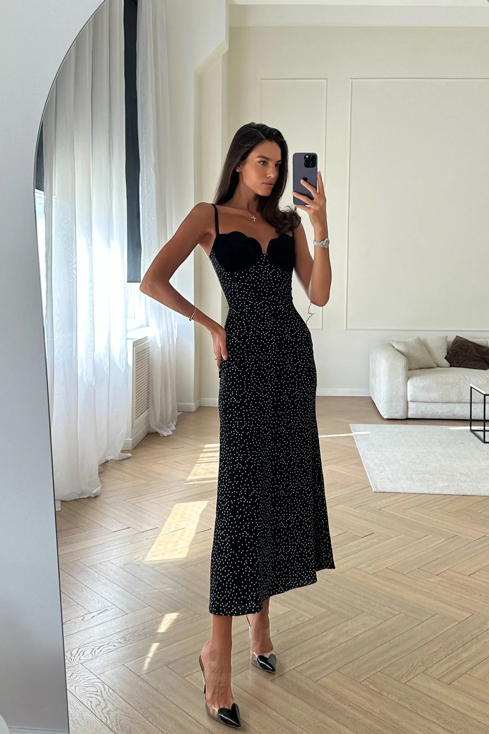 Black - A woman models a black formal maxi dress featuring a velvet sweetheart bustier, spaghetti straps, and an all-over white polka dot pattern.