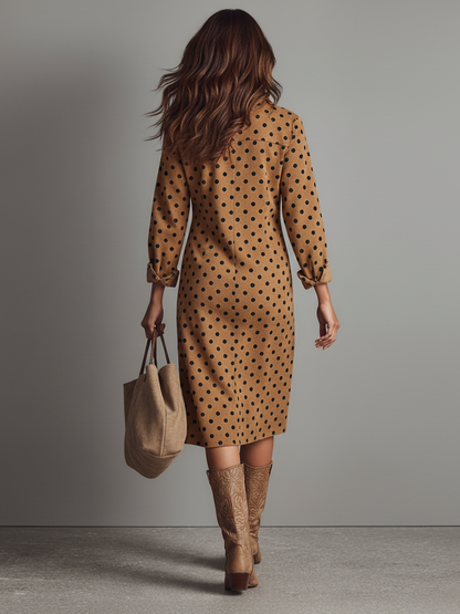 Brown - A woman walking in a tan and black polka dot midi shirt dress with long sleeves, a button-up front, and chest pockets, styled with knee-high brown leather boots and a suede tote bag.