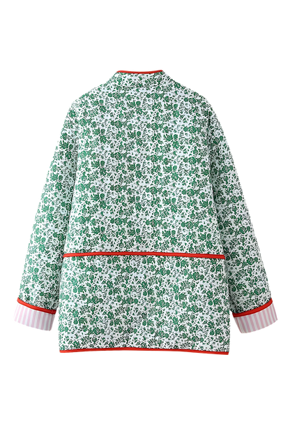 Green - Woman wearing a green and white ditsy floral quilted jacket with red piped trim over a pink striped dress.