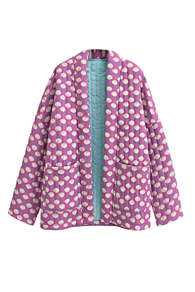 Woman wearing a pink quilted mid-length jacket with a white floral pattern, styled open over a white top and light blue jeans.